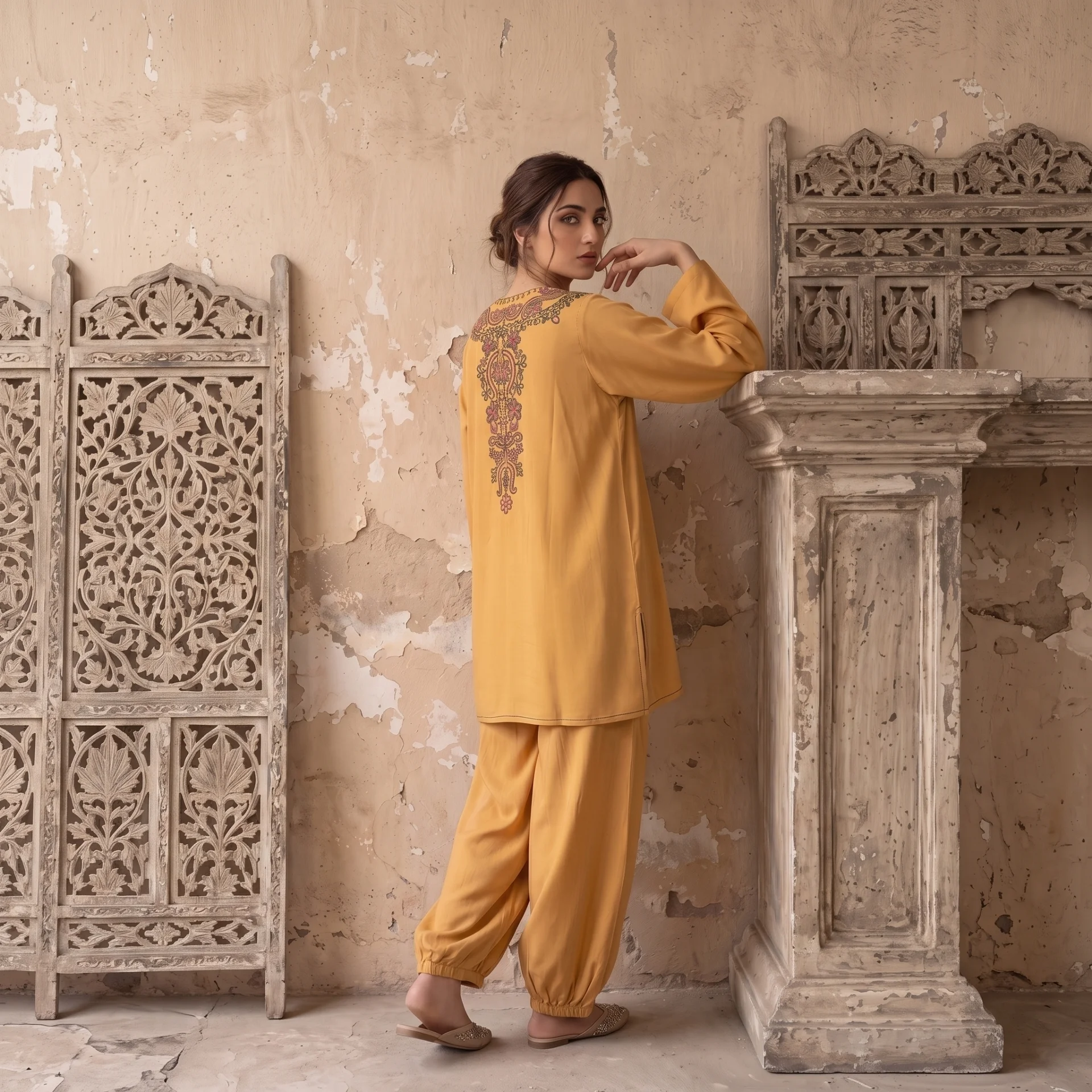 Model in a mustard linen co-ord beside a carved stone pillar